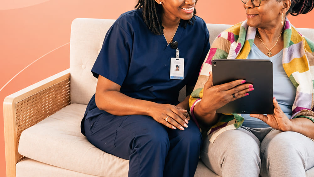 A caregiver and a resident looking at a tablet together